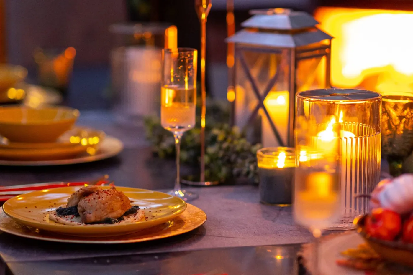 A plated course and a glass of sparkling wine by lantern light