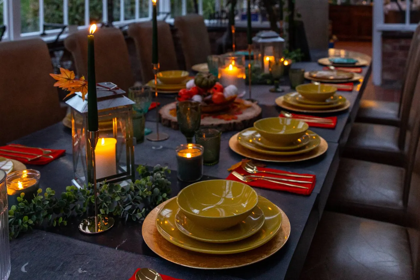 A long candlelit dining table set inside the glasshouse