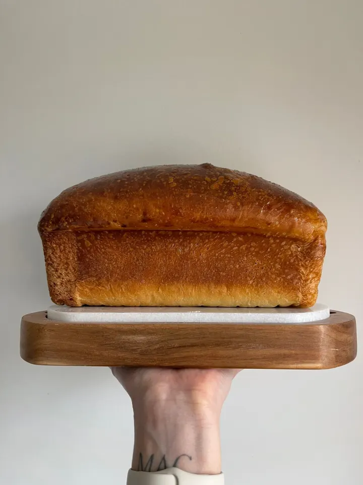 A golden signature sourdough brioche tin loaf on a wooden board