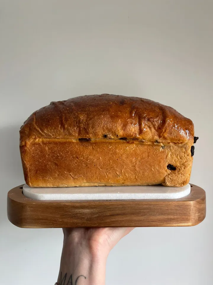 A spiced fruit sourdough brioche tin loaf on a wooden board